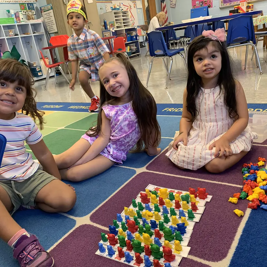 Preschool classmates building colorful patterns together on the classroom rug